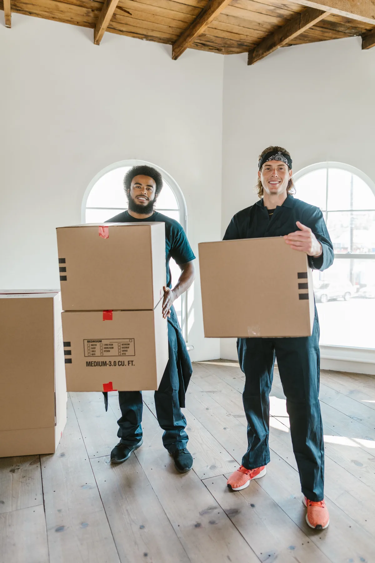 Professional movers carrying carefully packed boxes in a home